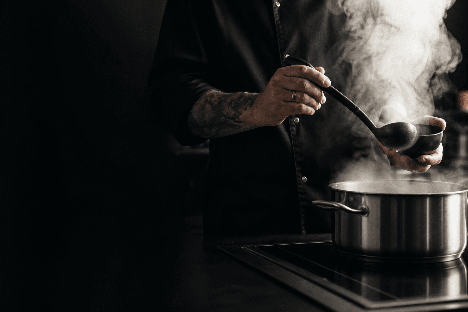 Chef at the range, steam rising from the pot